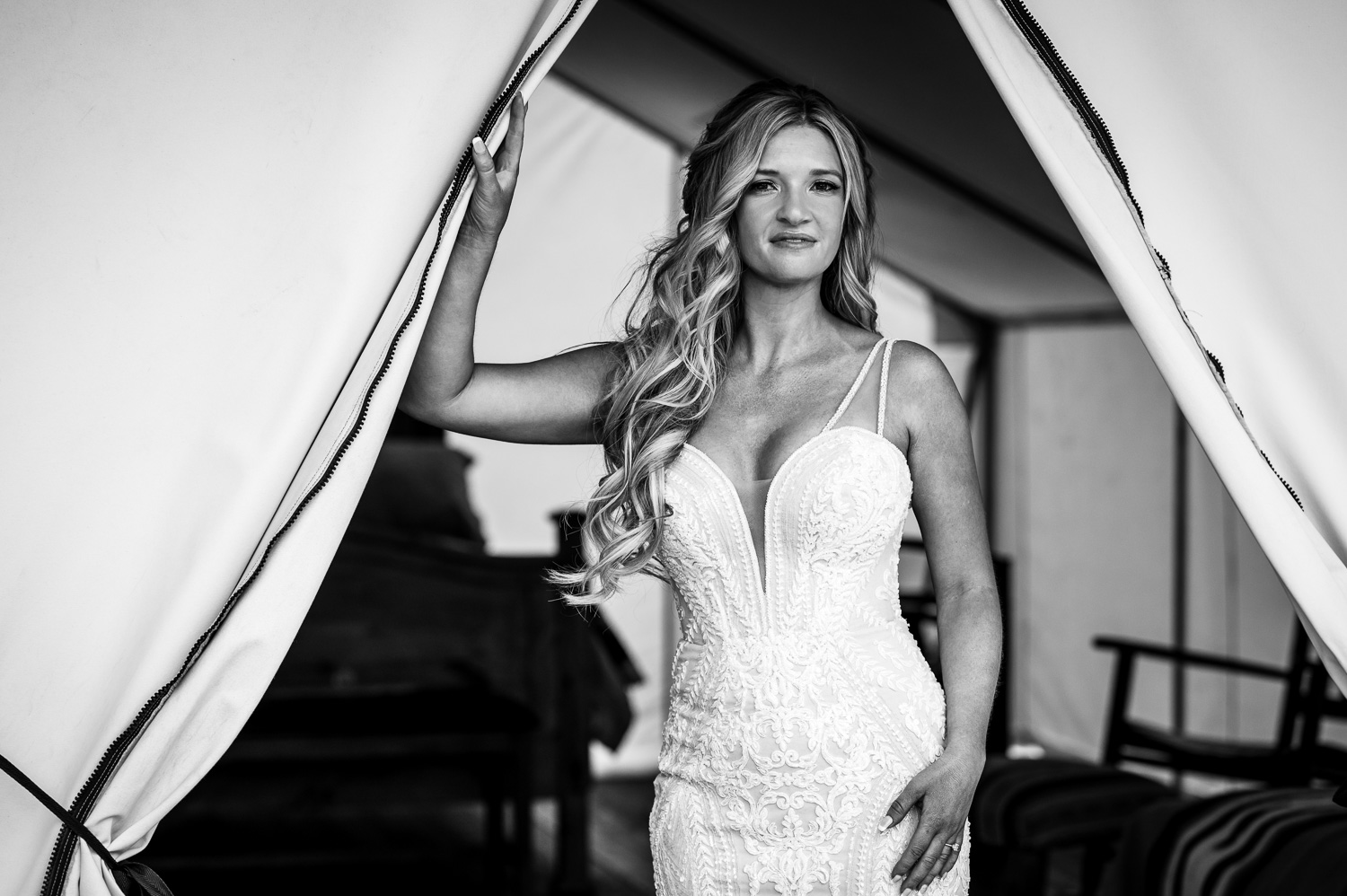 Bride looks fierce and stunning standing inside doorway of glamping tent